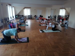 Grupa kobiet ćwiczących na sali na matach