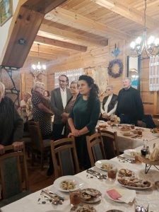 Grupa osób na sali przy zastawionych stołach